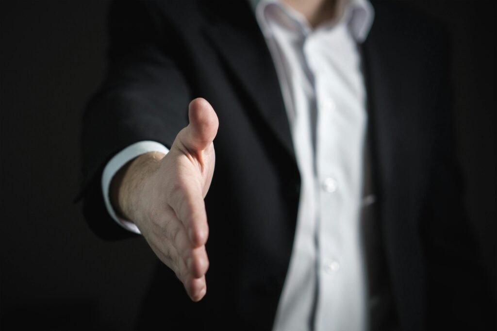 Derecho Civil Close-up of a businessman extending hand for a handshake, symbolizing agreement and partnership.
