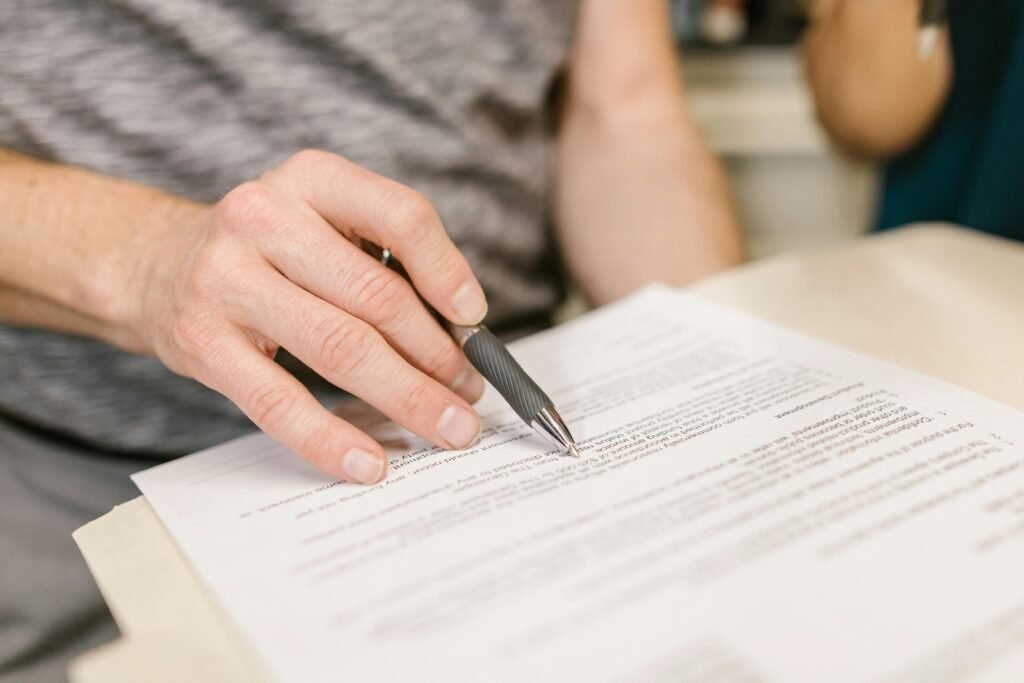 Derecho Laboral Close-up of a person's hand signing an important legal document with a pen indoors.